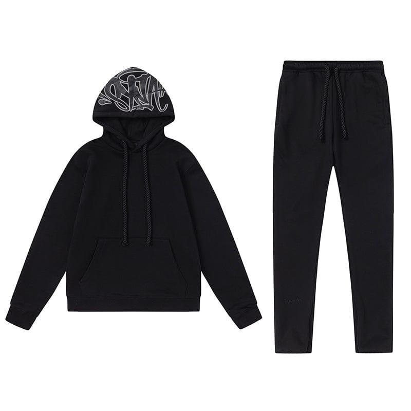 The Syna World Tracksuit Set features a black graphic hoodie with a front pocket, white graffiti print on the hood, and matching black flared drawstring pants for a bold urban style.