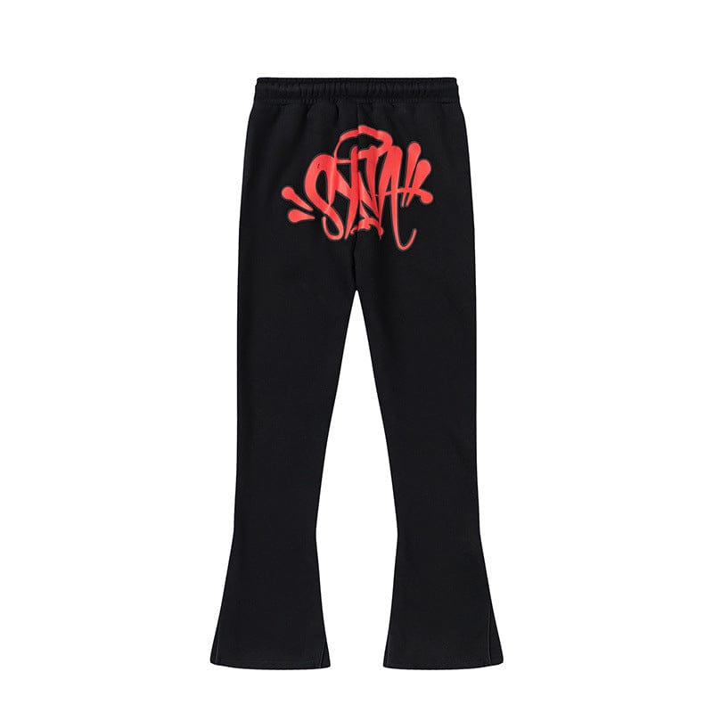 Syna World Graphic Tracksuit Pants in black feature a red graffiti-style logo on the front, an elastic waistband, and slightly flared legs. Available as matching pants in 4 colorways.