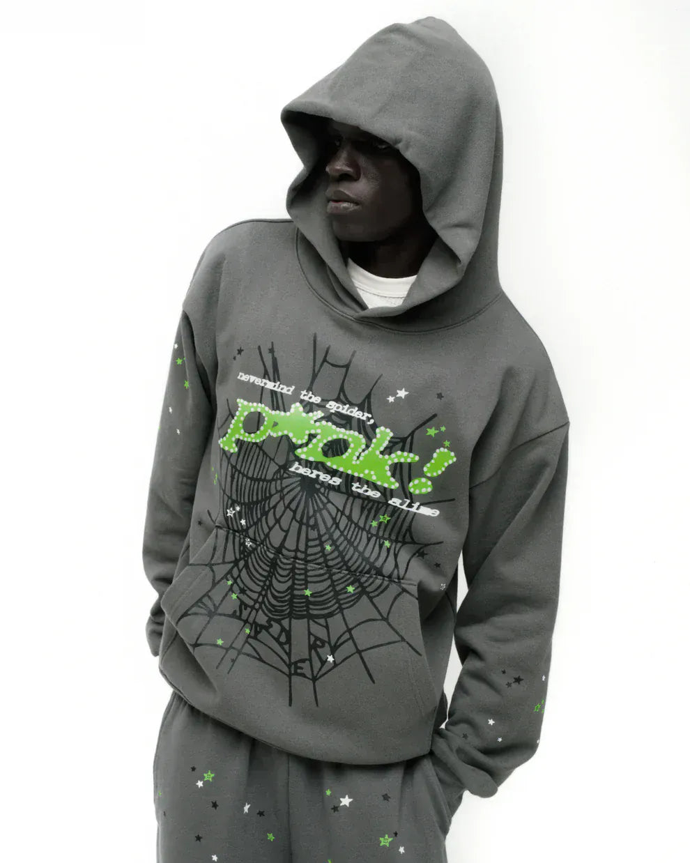 A person in an olive green Sp5der “P!nk! Hares the Slime” 440GSM heavyweight spider-web pullover hoodie, embodying streetwear vibes as they look to the side against a plain white background.