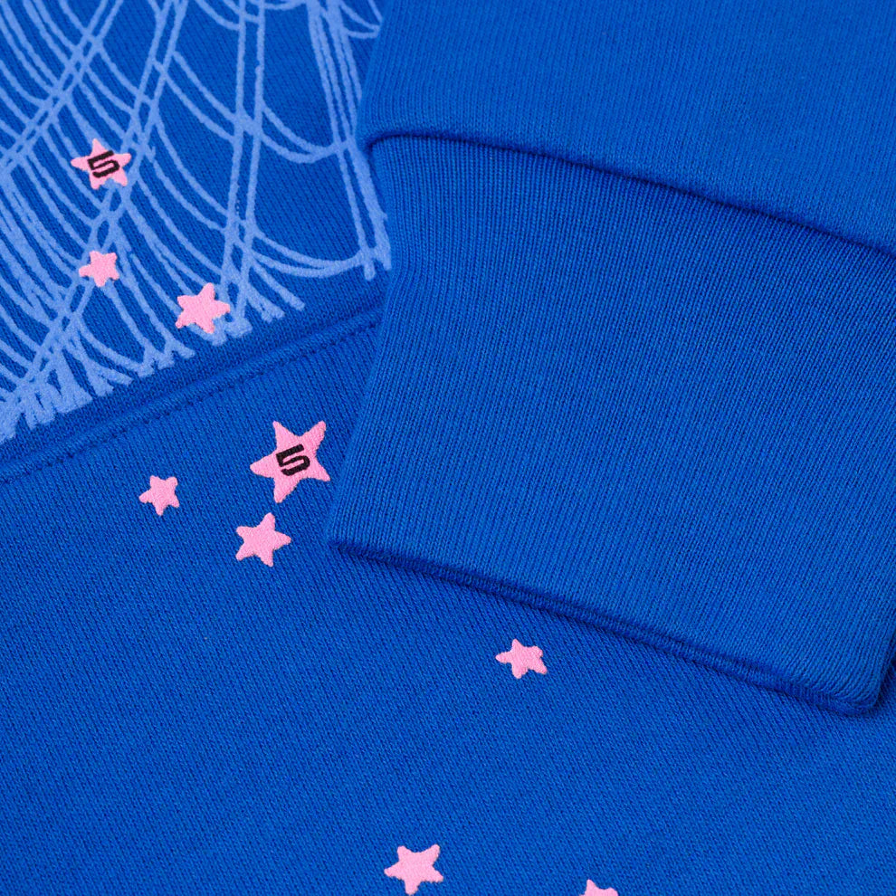 Close-up of the Sp5der “555” Hoodie – Royal Blue 440GSM Heavyweight Spider Web Streetwear Pullover, showing a ribbed cuff with pink star prints, number 5, and white line patterns—a standout for streetwear fans.