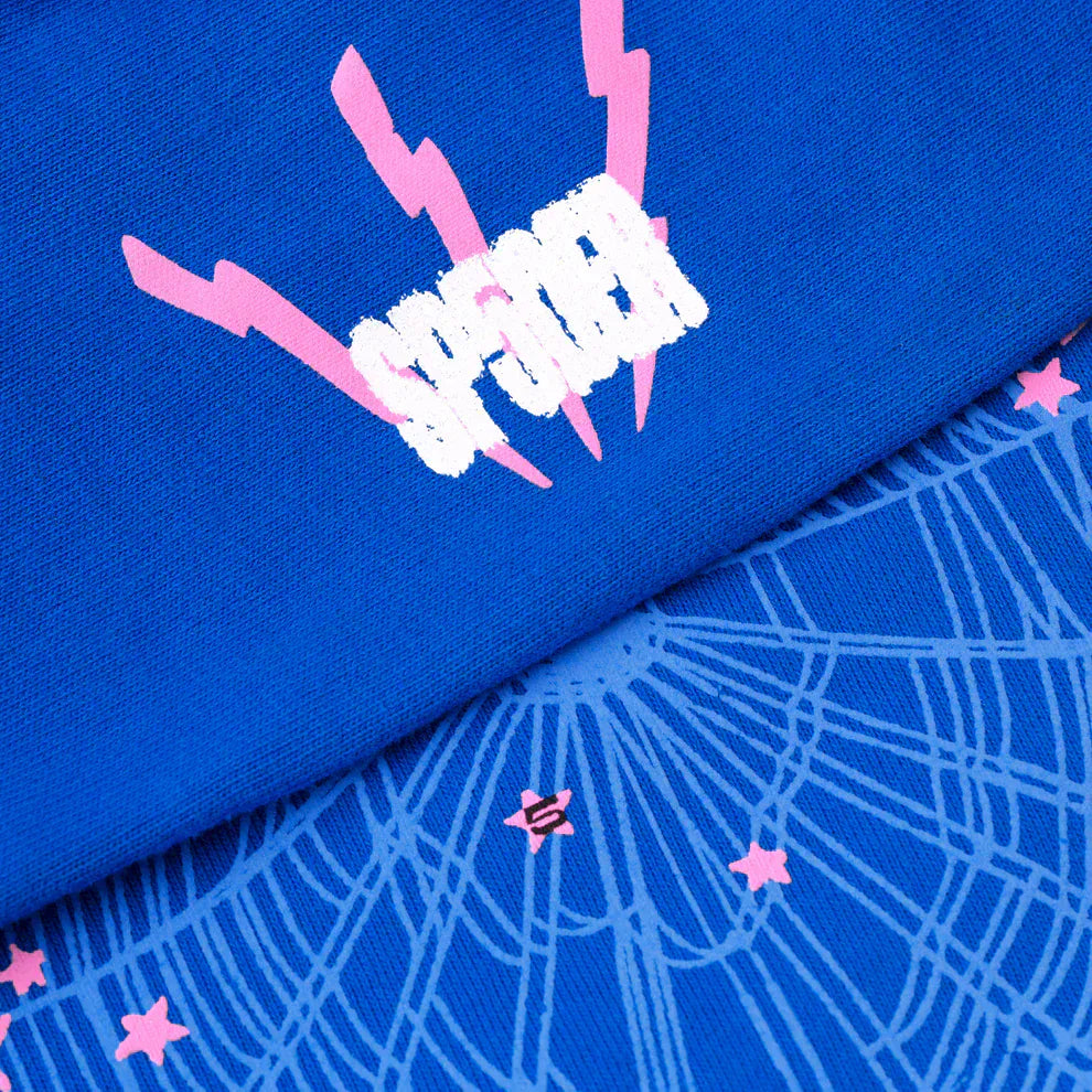 Close-up of the Sp5der “555” Hoodie in royal blue, featuring a white and pink SPIDER graphic with lightning bolts and pink stars over a web pattern, crafted from heavyweight 440GSM cotton fleece streetwear.