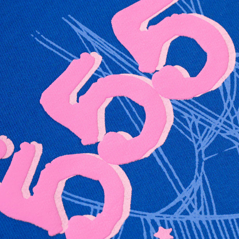 Close-up of royal blue 440GSM heavyweight cotton fleece from the Sp5der "555" Hoodie, featuring three pink stylized 505 designs layered over white abstract lines—a signature streetwear detail.