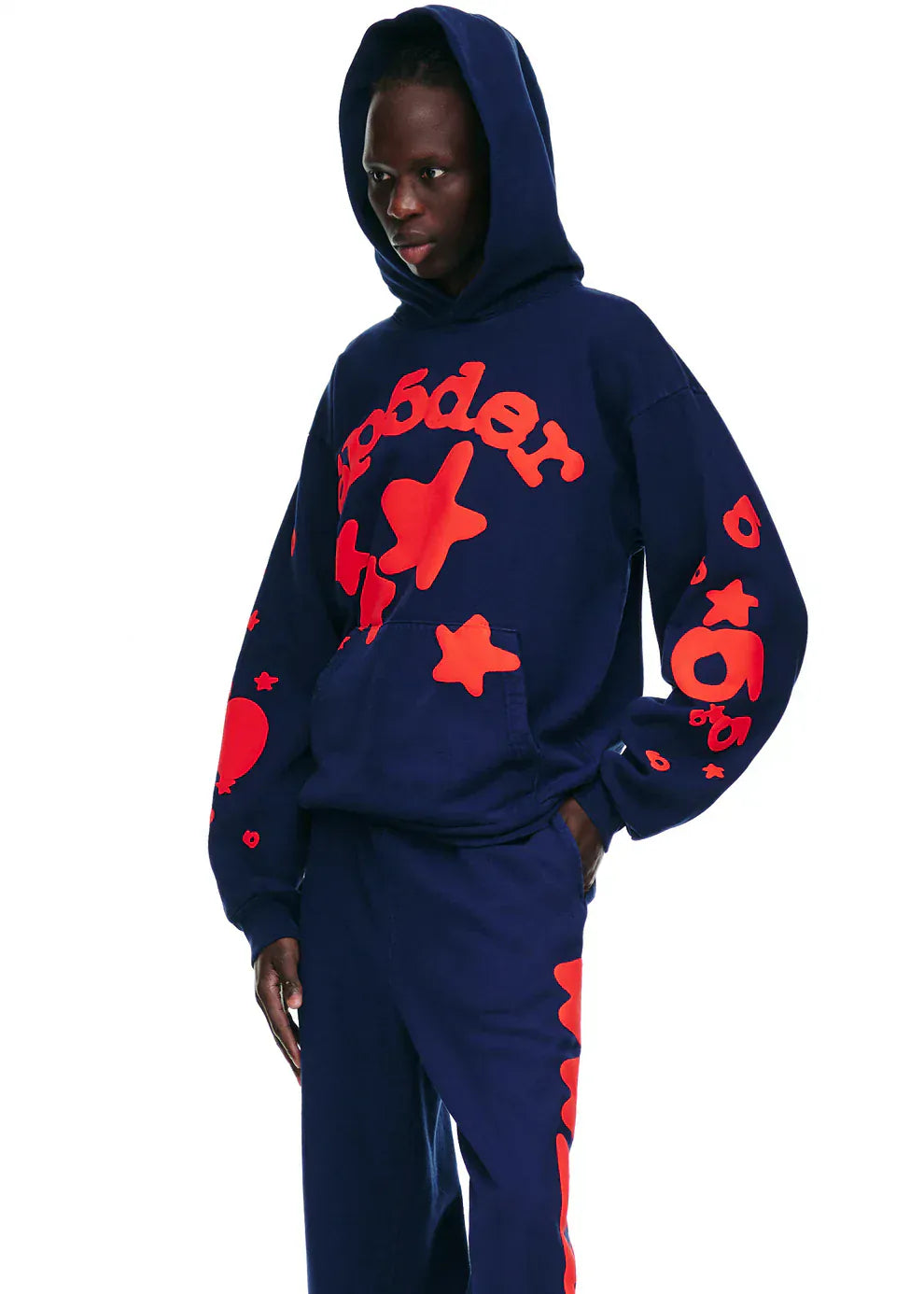 Wearing the Sp5der 440GSM Heavyweight Hoodie in navy blue with bold red star puff print, this look stands out against a white backdrop—an ideal streetwear nod to Y2K fashion.