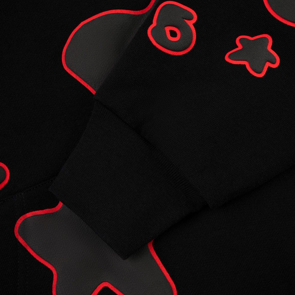 Close-up of the Sp5der 440GSM Heavyweight Star Hoodie – Black & Grey, an oversized streetwear pullover featuring red and gray outlined stars, symbols, and the number 8 on the sleeve and body.