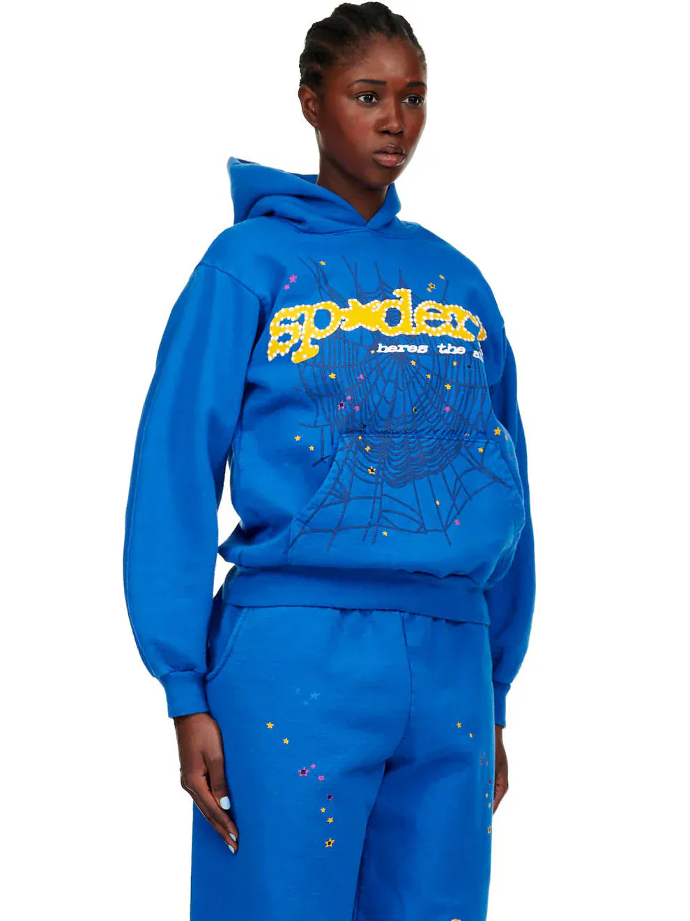 Wearing the Sp5der “Hares the Slime” Hoodie (440GSM) in royal blue, featuring a fuzzy yellow spider-web logo and vibrant graphic details, for a bold standout streetwear look.