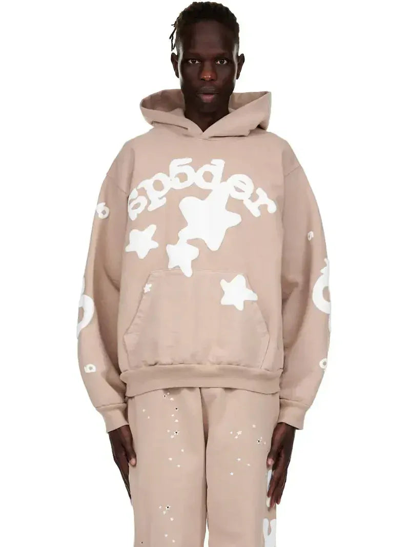 Someone wearing a Sp5der Star Hoodie – Brown & White 440GSM Heavyweight Oversized Streetwear Pullover, paired with beige pants featuring white star and circle patterns.