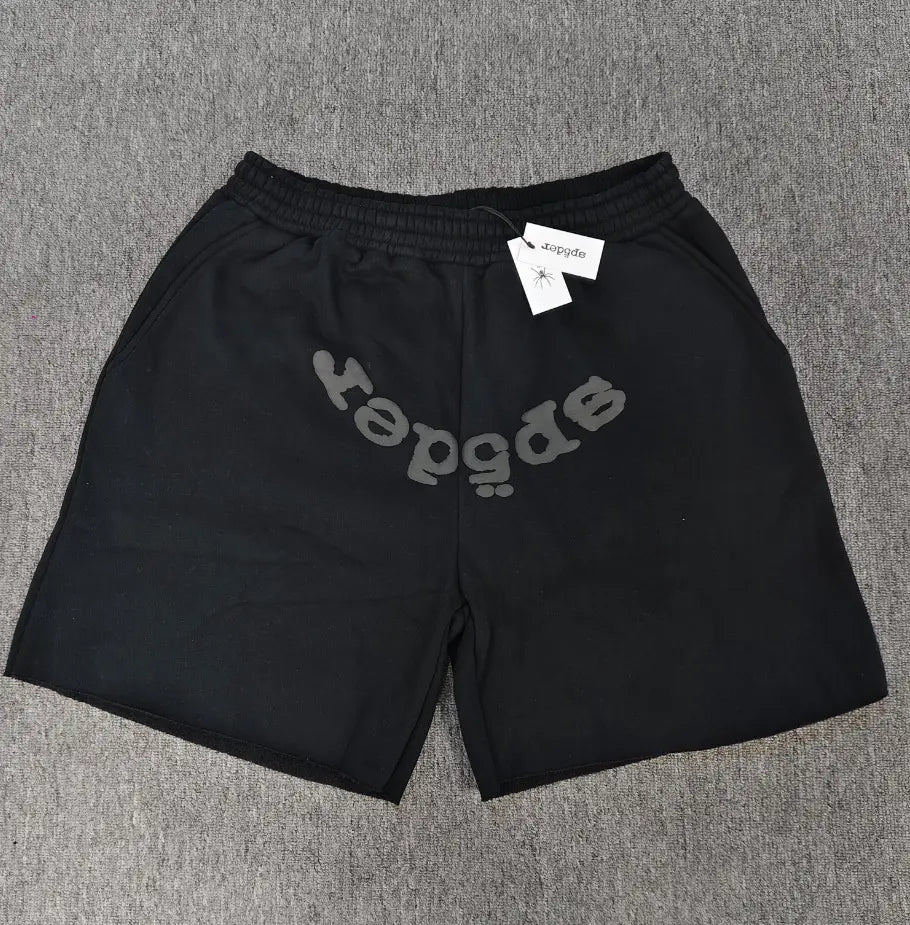Black Sp5der jogger shorts with gray arched logo print on the front, laid flat on a gray surface