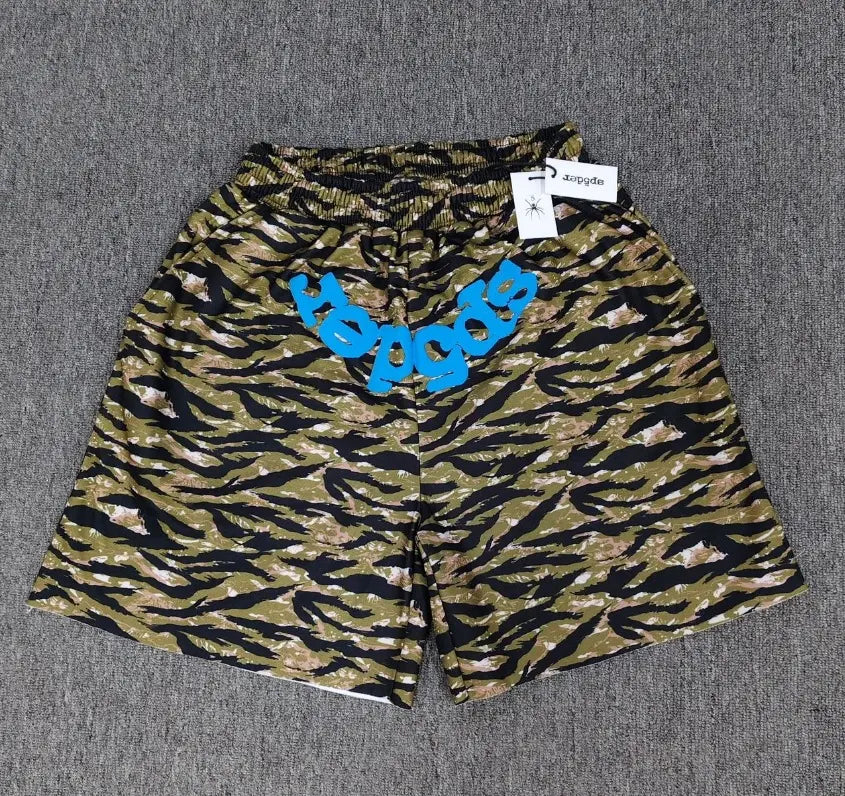 Sp5der green tiger stripe print jogger shorts with blue front logo graphic, laid flat on grey surface