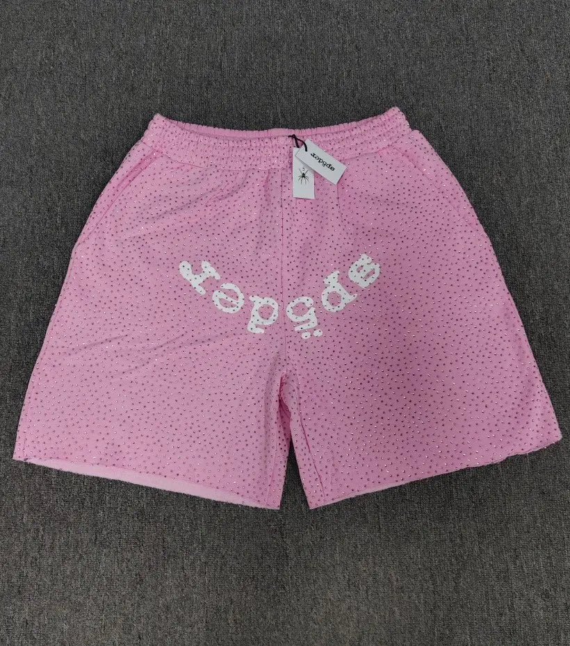 Pink Sp5der jogger shorts with dot texture and white front arc logo print, relaxed fit, laid flat on grey surface