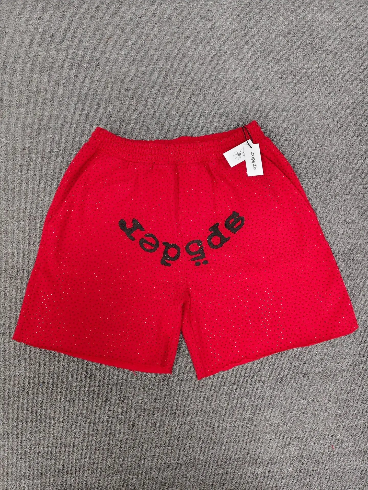 Red Sp5der shorts with a black arched front logo graphic and all-over rhinestone detailing