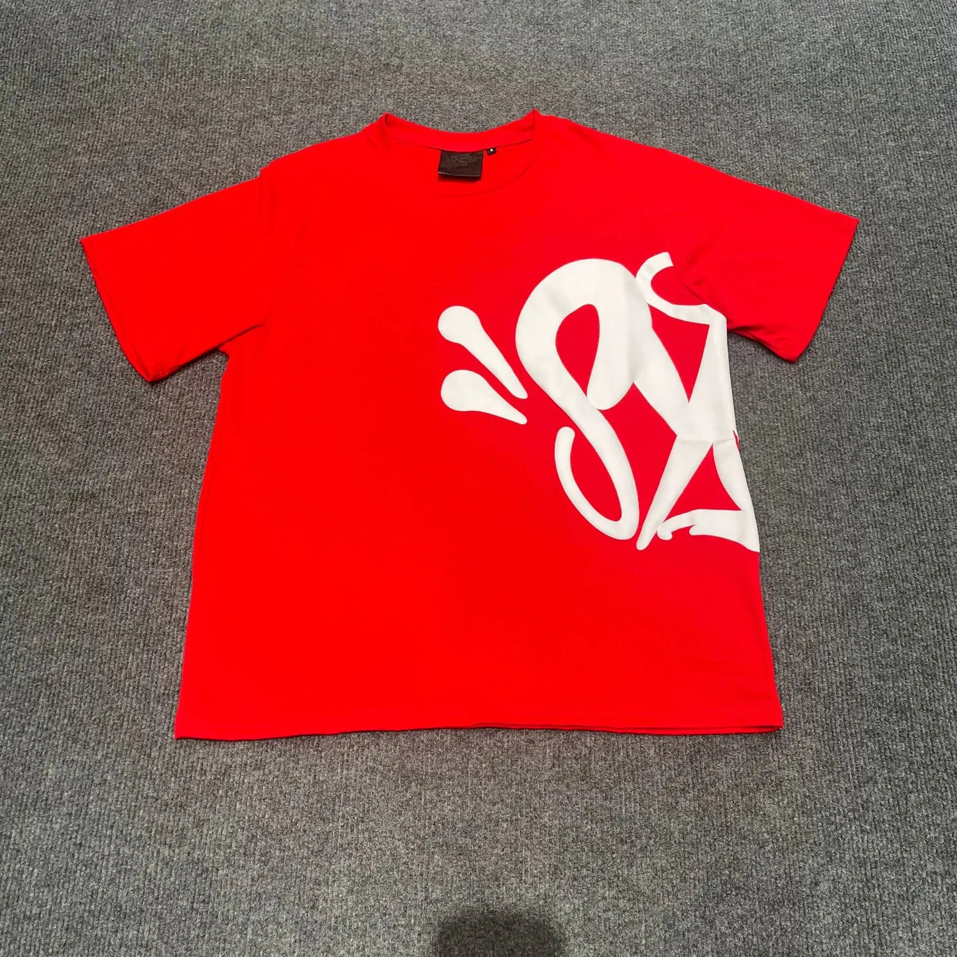 Red oversized cotton T-shirt with large white graphic letter print on the front, laid flat